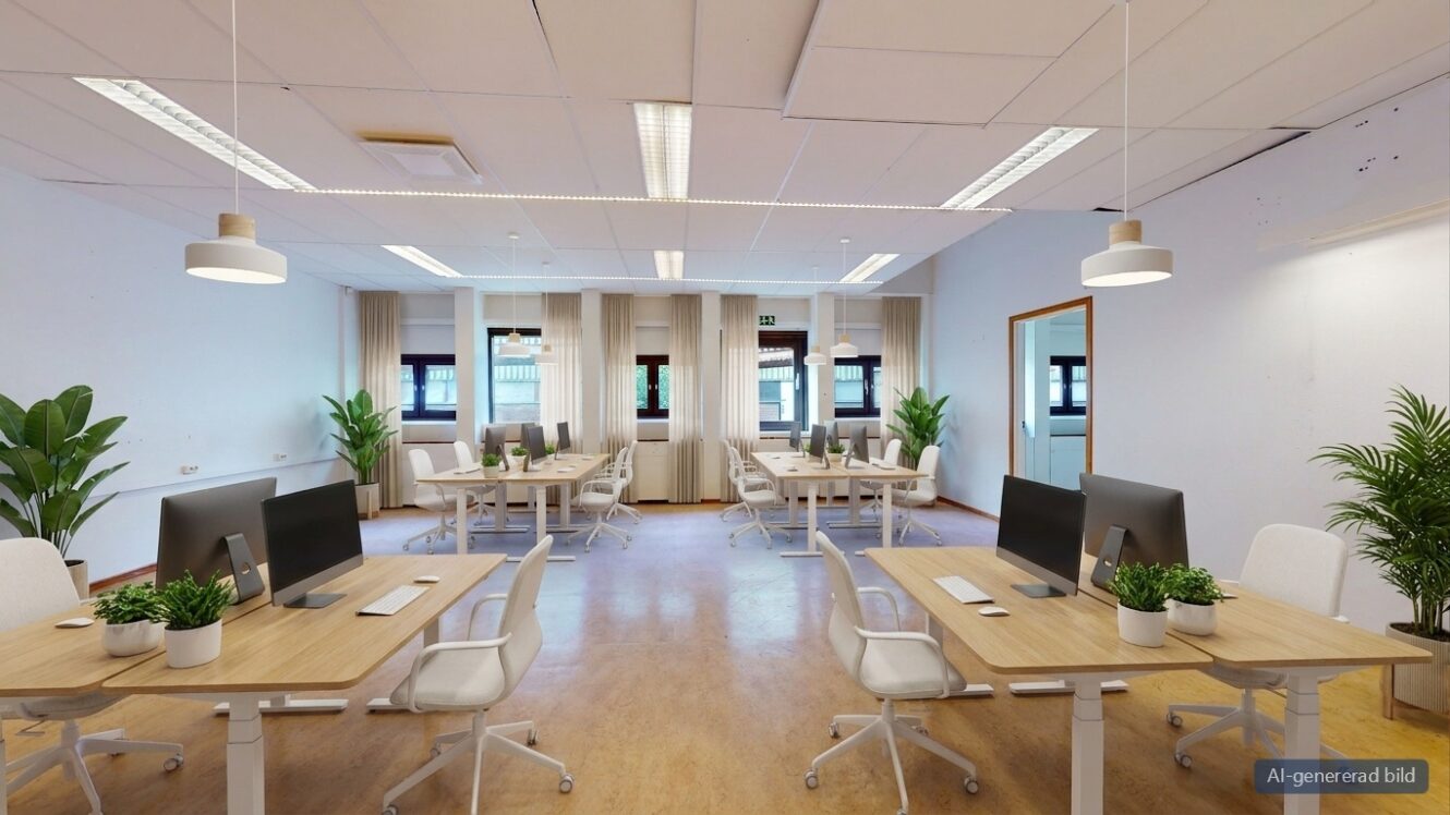 Ett kontor med öppen planlösning med flera rader av träskrivbord, vita stolar, datorskärmar och krukväxter.