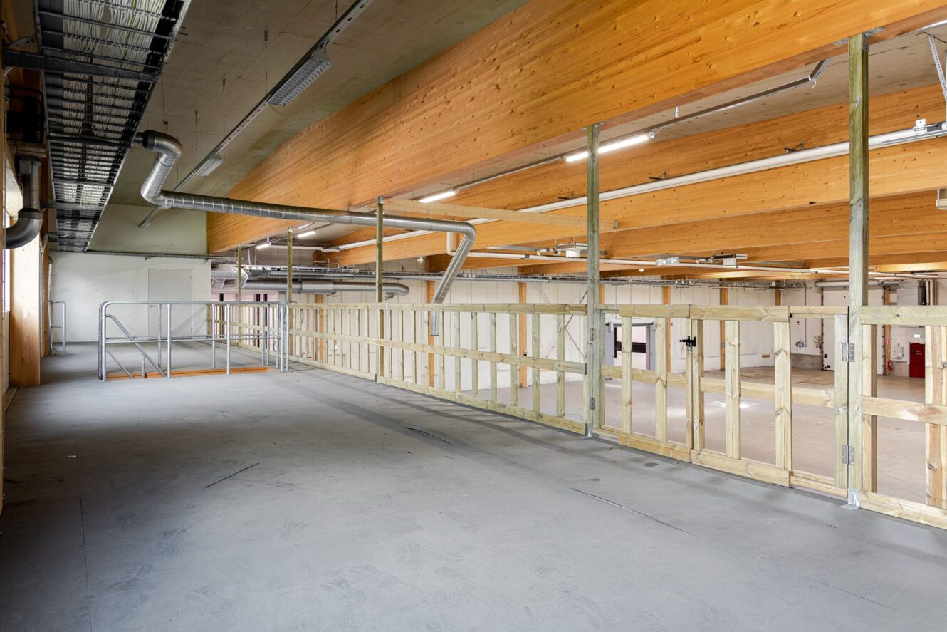 Delvis konstruerat inre utrymme med synliga träbjälkar, ofärdiga väggar, metallkanaler och en öppen golvyta.