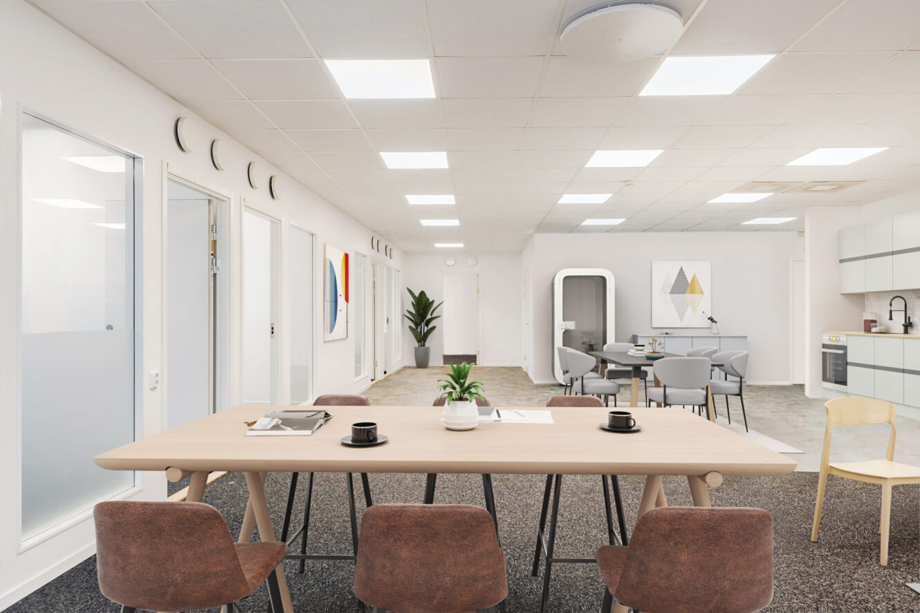 Modernt kontorsrum med mötesbord i trä, bruna stolar, pentry och minimalistisk inredning med bland annat abstrakt väggkonst och en krukväxt.