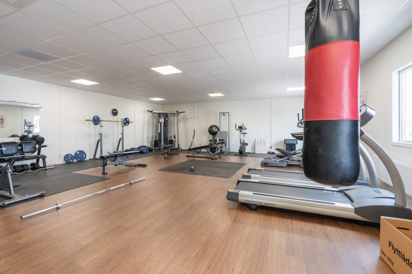 Rymligt gymrum med diverse utrustning, bland annat löpband, viktmaskiner, fria vikter, boxningssäck och trägolv.