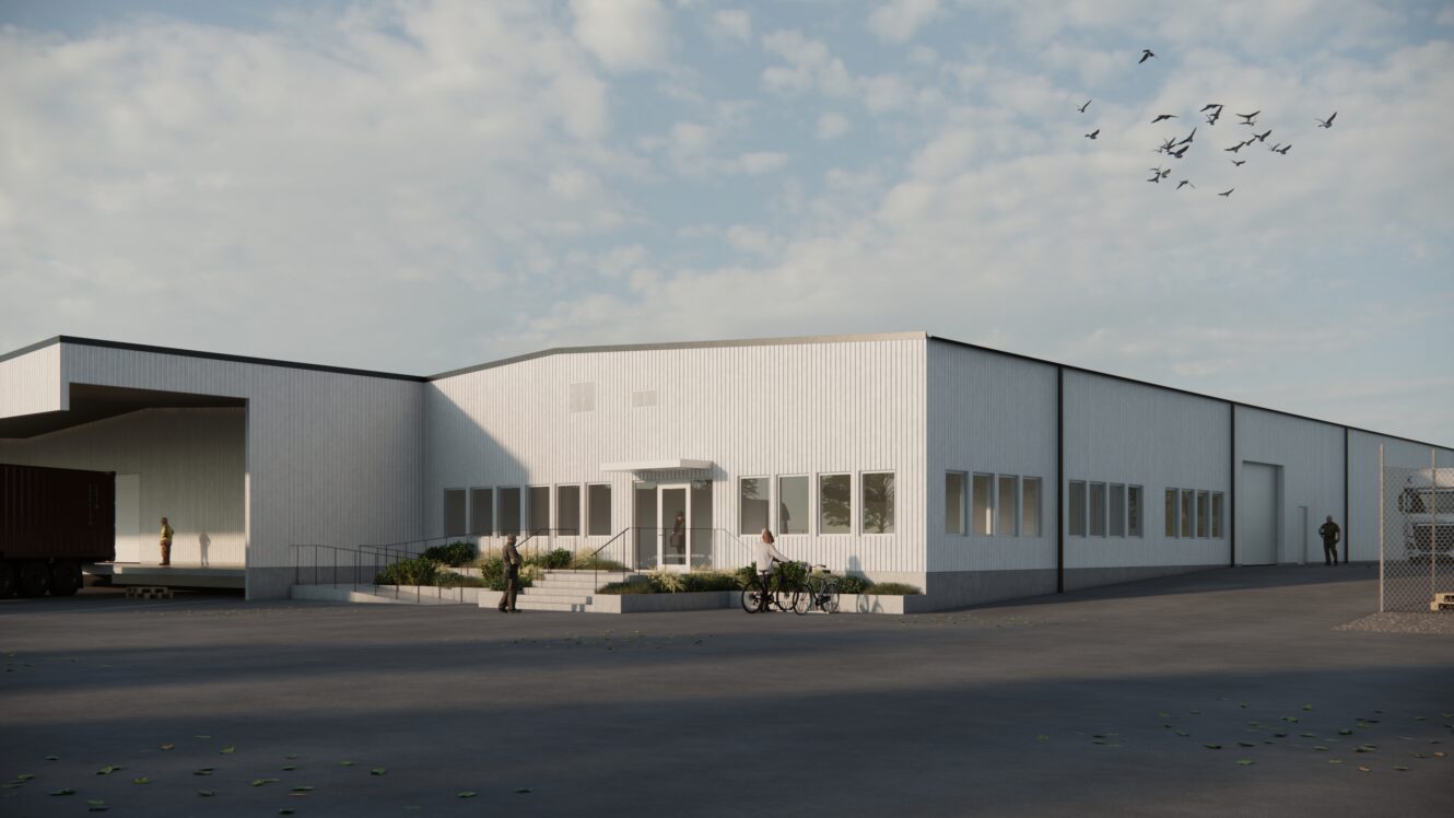 Ett stort, vitt industriellt lager med flera fönster och en ramp, omgivet av asfalterad mark, med människor och fåglar synliga i scenen.