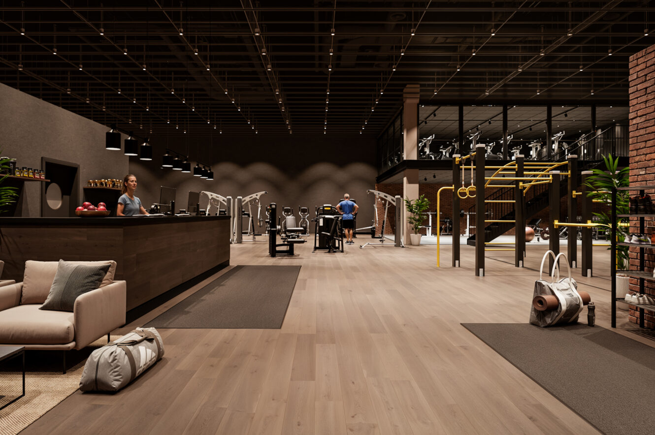 Modern gyminredning med olika träningsredskap, en reception med receptionist, loungeområde och människor som tränar på maskiner.
