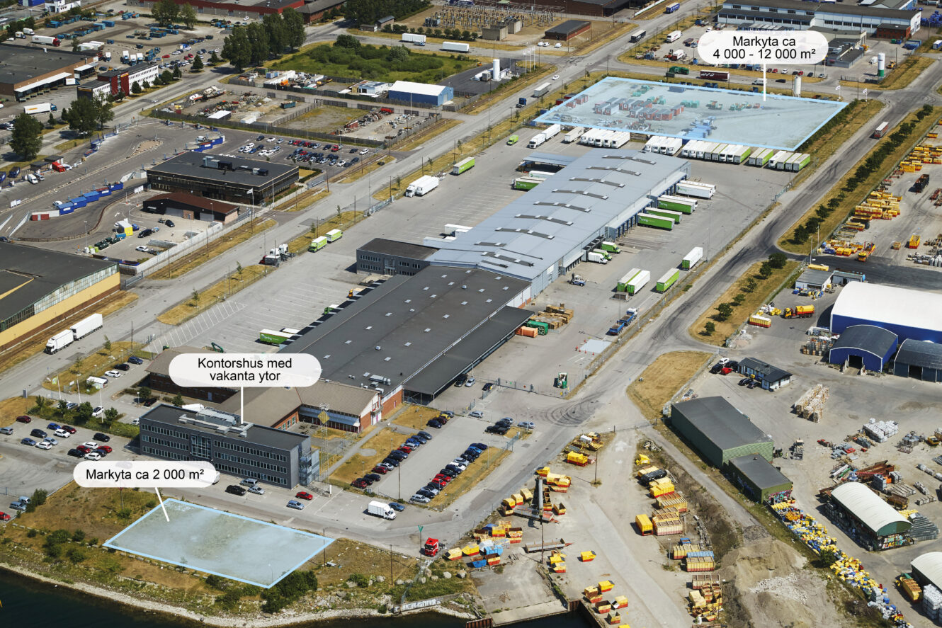 Flygfoto över ett industriområde med lagerlokaler, kontorsbyggnader, parkeringsplatser, containrar och markerade lediga tomter.