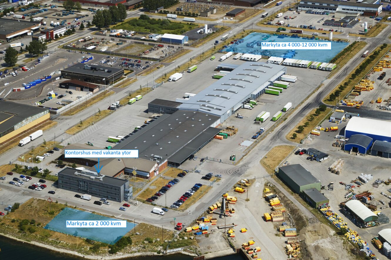 Flygfoto över en industrianläggning med markerade kontors- och lagerutrymmen, omgivande parkeringsplatser, lastbilar och närliggande förvaringsgårdar.