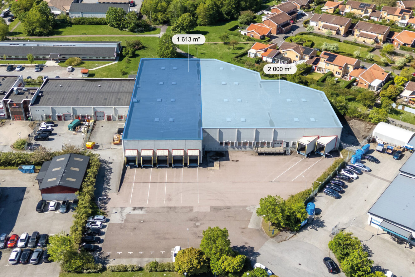 Flygfoto över ett stort lagerkomplex med två sektioner markerade 1.613 m² och 2.000 m², omgivet av tomter och byggnader.