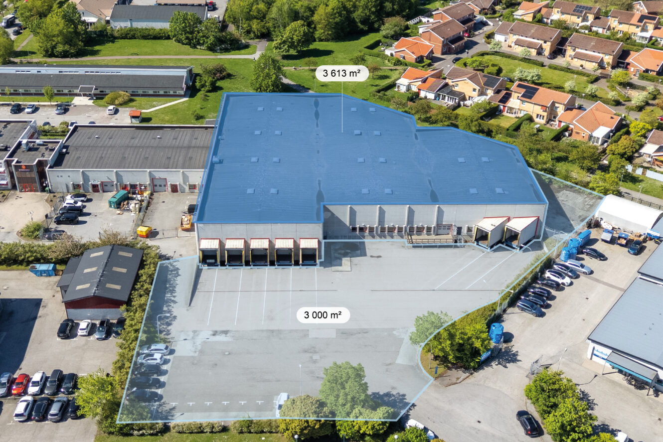 Flygfoto över ett kommersiellt lager med markerade ytor märkta 3.613 m² och 3.000 m² på en parkeringsplats, omgiven av byggnader och bilar.