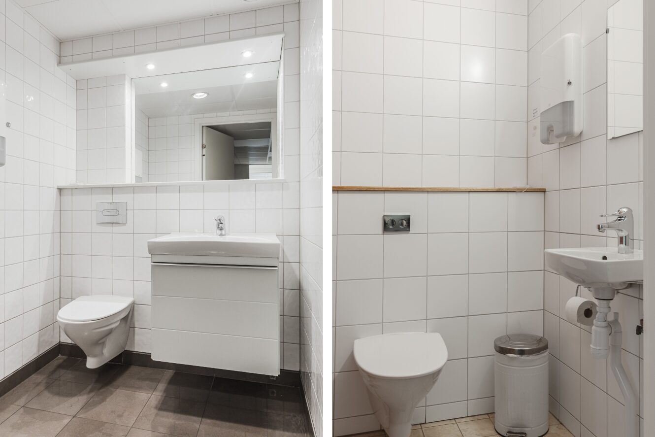 Två moderna badrum med vitkaklade väggar; varje badrum har en väggmonterad toalett och handfat, med en spegel i det ena och en papperskorg och tvålpump i det andra.
